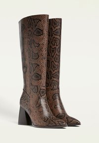 Brown snake-print knee-high boots with a pointed toe and block heel. Textured exterior with contrasting black patterns. Sleek design.
