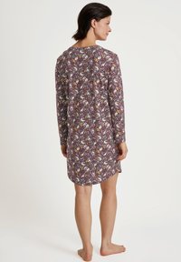Abito a maniche lunghe realizzato in tessuto morbido, con un motivo floreale multicolore su uno sfondo bordeaux. Taglio dritto con spacchi laterali.