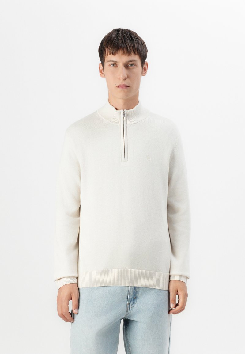 Hellbeige Zip-Up-Pullover mit hohem Kragen, gerippten Bündchen und Saum. Aus einem weichen Stoff gefertigt und mit einem kleinen Logo auf der Brust versehen.