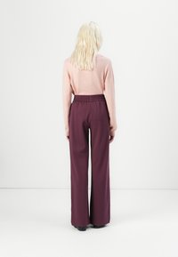 Light pink knit sweater with long sleeves, paired with high-waisted, wide-leg maroon trousers featuring an elastic waistband.