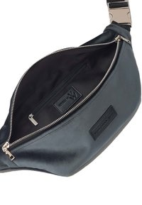 Riñonera de nailon negro con cremallera plateada, bolsillo interno y parche de logo texturizado. Superficie lisa, correa ajustable y diseño moderno.