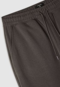 Ciemnoszare dresy wykonane z miękkiego materiału, z elastycznym paskiem w pasie z troczkiem, bocznymi kieszeniami oraz luźnym krojem.