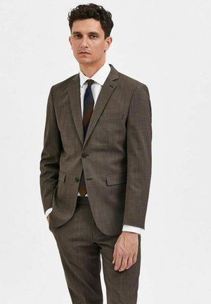 Costume marron à motifs avec une veste à un bouton et des revers crantés. Chemise habillée blanche et cravate rayée multicolore. Design ajusté.