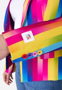Colorful blazer in stripes of pink, blue, and yellow. Features a fabric tag and four multicolored buttons on the cuff. Smooth texture.