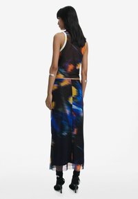 Sleeveless dress with a flowing silhouette, featuring a vibrant abstract print in blue, orange, and black. Accented with silver hardware.