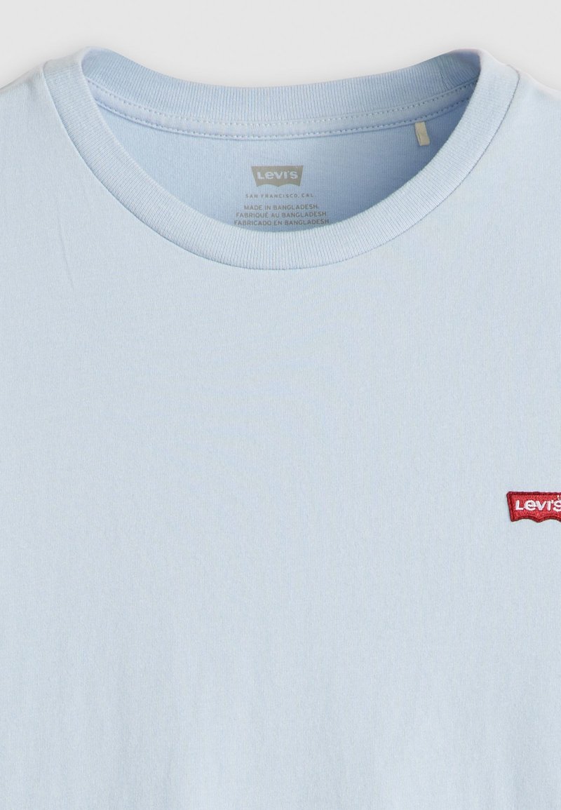 Camiseta de algodón azul claro con cuello redondo y mangas cortas. Presenta un pequeño logo bordado en rojo de Levi's en el lado izquierdo del pecho.