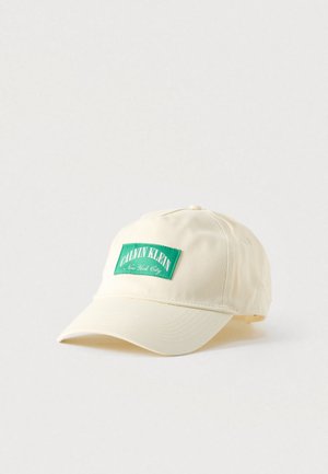 Helebeežikaunistusega helebeežist puuvillast nokamüts, millel on roheline ristkülikukujuline plaastriga tekstidega "CALVIN KLEIN" ja "New York City". Kaardus nokadisain.