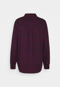 Long-sleeve shirt in dark purple fabric featuring a subtle repeated text pattern in contrasting pink. Button cuffs and back collar detail.