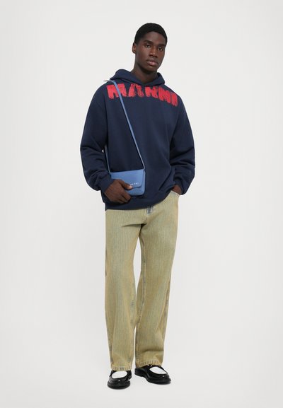 Námornícky sveter s červenou grafikou, svetlé široké pruhované nohavice, čierne topánky a modrá crossbody taška. Jednoduchý, neformálny mestský outfit.