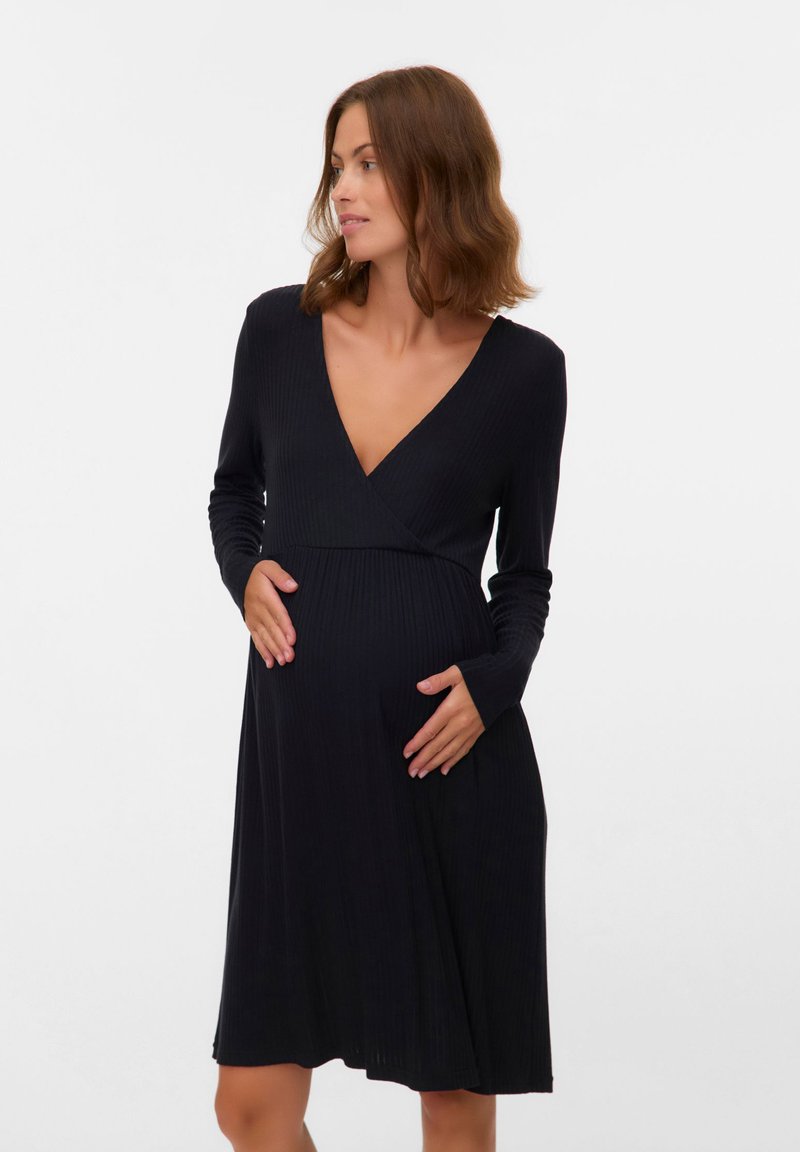 Czarna prążkowana sukienka ciążowa z długimi rękawami, głębokim dekoltem w serek i sylwetką w kształcie litery A, wykonana z miękkiego materiału, z luźną spódnicą.