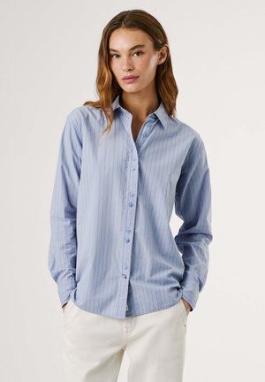 Camicia azzurra chiara con righe verticali rosse, maniche lunghe e colletto classico. Tessuto morbido con una vestibilità rilassata.