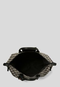 Sac à motifs noir et blanc avec fermeture éclair, dotée de poignées en cuir noir et d'un intérieur vide spacieux.