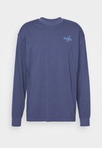 Hosszúujjú sötétkék pamut póló, bal mellen egy kis kék hímzett "nike" logóval. Kerek nyakú és bordás mandzsettákkal.