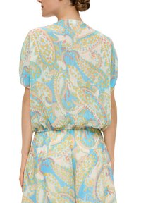 Lichte blouse met een zachte, vloeiende textuur. Heeft een paisleypatroon in blauw, geel en roze. Korte mouwen en een elastische taille.