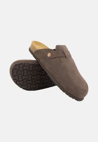 Braune Wildleder-CLogs mit einer strukturierten schwarzen Gummisohle. Verfügt über einen dezenten seitlichen Schlitz und eine dekorative Metallknopfdetail.