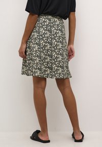 Floral skirt with a black background, featuring white flowers and a flared design. Made of lightweight fabric, knee-length, with a smooth texture.