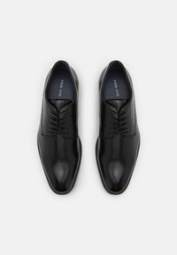 Chaussures habillées en cuir noir avec une finition lisse, à bout rond et cinq paires d'œillets pour les lacets, présentant un motif texturé subtil sur les côtés.