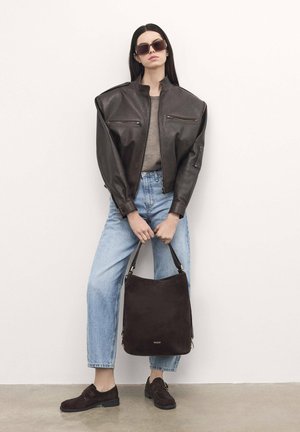 Brown leather jacket with padded shoulders, gray top, light blue high-waisted jeans, dark brown suede shoes, and a dark brown bag.