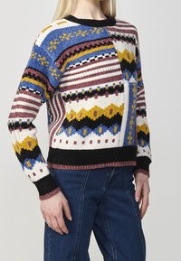 Maglione lavorato a maglia con strisce multicolori e motivi in blu, bordeaux, giallo e nero. Polsini e orlo a coste che aggiungono texture.