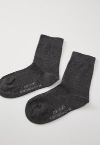 Calcetines de algodón gris con textura acanalada, corte clásico y punta redonda, con "ca-soft" impreso en el lado en gris claro.