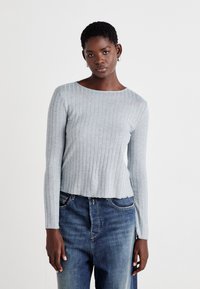 Lys grå stripete langermet topp med rund halsringning, kombinert med mørkeblå jeans. Stoffet har en myk tekstur og en tettsittende design.
