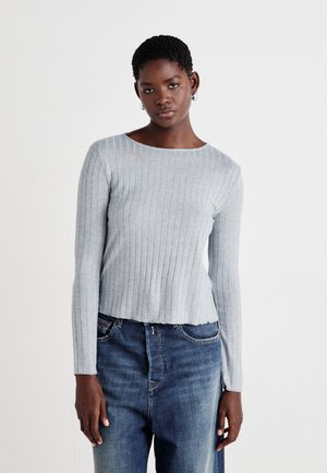 Light grey ribbed long-sleeve top with a round neckline, paired with dark blue jeans. Fabric has a soft texture and a fitted design.