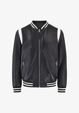 Giacca bomber in pelle di colore blu navy con strisce bianche a contrasto. Dotata di zip frontale, polsini e orlo a costine. Due tasche laterali con zip. Texture liscia.