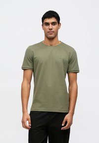Olivovo zelené bavlnené tričko s krátkymi rukávmi a okrúhlym výstrihom. Na ľavej strane na hrudi je malá logo "BOSS". Jemná textúra.