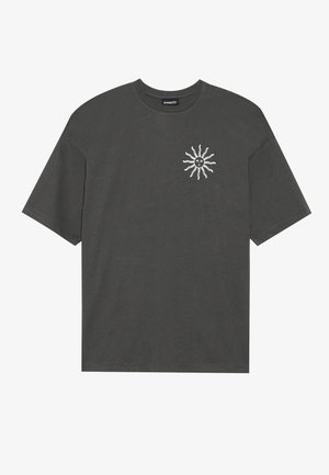 Šedé bavlněné tričko s volným střihem, které na levé části hrudi zdobí bílá grafika slunce. Krátké rukávy a kulatý výstřih.
