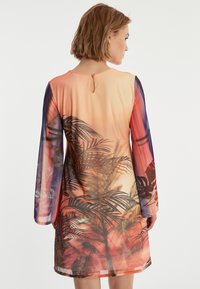 Robe à manches longues en tissu léger, dégradé d'orange à violet. Présente un imprimé de feuilles de palmier et un détail en forme de trou de serrure au dos.