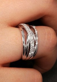 Silberner Mehrbandring mit geschwungenen Designs, der funkelnede Akzente von eingelassenen Steinen entlang eines Bandes aufweist. Glatte, glänzende Oberflächenverarbeitung.