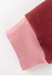 Baumwoll-Sweatshirtärmel mit einem Blockdesign in Dunkelrot und Pink, mit glatter Textur und gerippten Bündchen.
