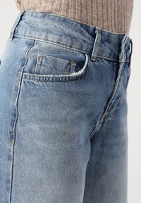 Light blue denim jeans with a slightly faded finish, featuring a traditional five-pocket design and contrasting stitching.