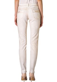 Tight-fit vita jeans med en slät yta, femfickorsdesign, synliga sömmar och en subtil logotypdetalj på baksidan.