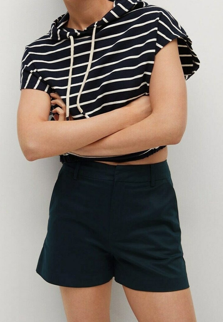 Personne portant un short bleu marine sur mesure et un sweat à capuche à manches courtes rayé bleu marine et blanc avec cordons, bras croisés.