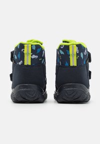 Scarpe per bambini di colore blu navy con tessuto testurizzato, dettagli verde brillante e due cinturini in velcro. La parte posteriore presenta un motivo colorato e strisce riflettenti.