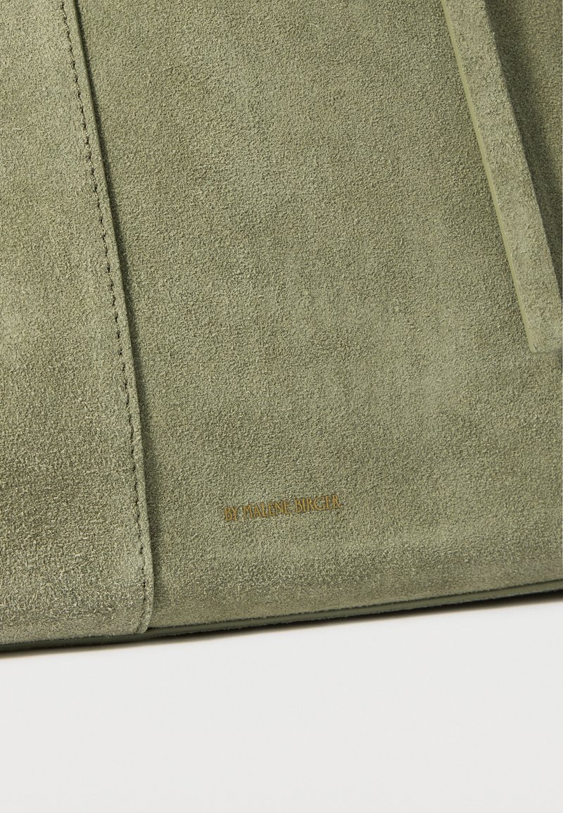 Sac en suède vert avec une surface texturée, un design minimaliste et un logo embossé en or. Comprend un rabat angulaire et des détails de couture.