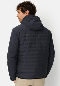 Donkerblauwe geïsoleerde jas met een capuchon, met een doorgestikte textuur, glad materiaal en elastische manchetten. Lichtgewicht en nauwsluitend ontwerp.