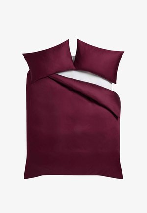 Doppelbett mit burgunderrotem Bettbezug und passenden Kissenbezügen auf weißem Laken, von oben gezeigt mit einer Ecke leicht zurückgefaltet.