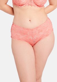 Mutandine in pizzo di un delicato corallo, con motivi floreali, bordi ondulati e una consistenza delicata. Il design a vita media migliora il comfort.