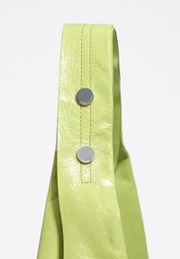 Zielona teksturowana sztuczna skórzana taśma z dwoma srebrnymi zatrzaskami, z widocznym szwem wzdłuż krawędzi, prezentująca błyszczące wykończenie.