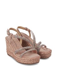Sandalias de cuña beige con base de yute trenzado, tiras cruzadas brillantes y correa en el tobillo ajustable. Textura suave similar al ante en la plantilla.