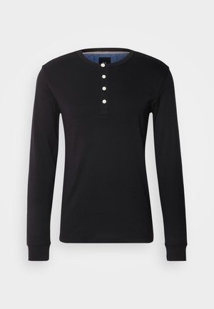 Camisa negra de manga larga hecha de tejido suave, con un cuello redondo, tapeta de botones con botones blancos y puños ajustados.