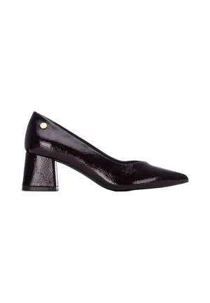 Zapato de salón de mujer de charol negro con tacón bajo tipo bloque y un pequeño emblema dorado redondo cerca del talón.