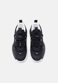 Μαύρα αθλητικά παπούτσια με πλέγμα επάνω μέρος, υφασμάτινες λεπτομέρειες, μαύρα κορδόνια και λευκή σόλα· θηλύκια στο πίσω μέρος για εύκολη φόρεση.