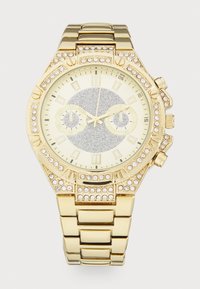 Montre-bracelet couleur or avec un bracelet en métal brillant, cadran argenté scintillant et accents en cristal entourant la lunette et le cadran. Elle comporte deux sous-cadrans.