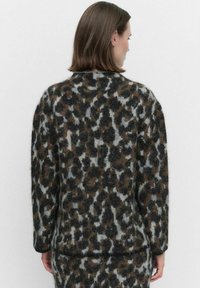Leopardmönstrad tröja i fluffig textur med nyanser av brunt, svart och grått; har rund hals och långa ärmar, samt en avslappnad passform.