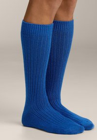 Calze blu fino al ginocchio realizzate in tessuto a costine. Presentano una texture liscia e un design aderente, terminando con punte arrotondate.