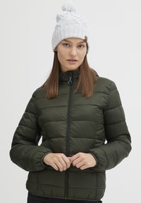 Olivengrønn puffjakke med horisontalt quiltet mønster, frontglidelås og høy krage. Kombinert med en lysegrå strikket lue med pom-pom.