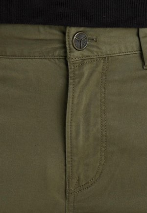 Pantalons en coton vert olive avec une fermeture éclair, un bouton de fermeture et des coutures contrastées le long des seams. Détail de rivet en métal présent.
